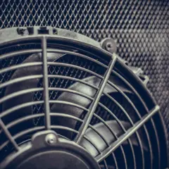 Ventola radiatore non parte. Dettaglio di una ventola con griglia metallica a nido d'ape sullo sfondo.