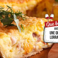 Une part de quiche lorraine garnie d'herbes, avec un texte "Que boire avec une quiche lorraine ?" et des verres de vin.