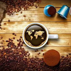 Tipi di cialde caffè e chicchi sparsi su un tavolo di legno. Una tazza di caffè con la mappa del mondo riflette il tema globale.