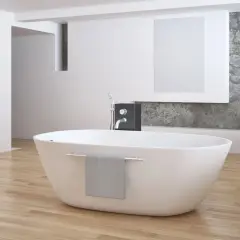 Eine freistehende **Badewanne mitten im Raum** auf hellem Holzboden, daneben ein moderner Wasserhahn und eine graue Handtuchhalterung.