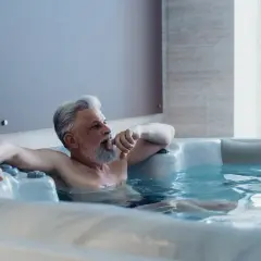 Starszy mężczyzna relaksuje się w jacuzzi. Czysta woda i odpowiednia chemia do jacuzzi zapewniają mu komfort.