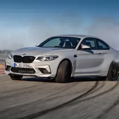 Un BMW M2 Competition CV derrapa en una pista, dejando estelas de humo y marcas de neumáticos.