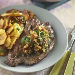 Une assiette de bavette à l'échalote, accompagnée de pommes de terre croustillantes et d'herbes fraîches. Un délice visuel et gustatif.