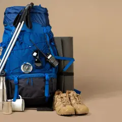 Jaki plecak w góry? Niebieski plecak, kijki trekkingowe, mata, buty, kompas, krótkofalówka i termos.