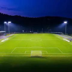 Piłkarskie boisko oświetlone mocnym oświetleniem stadionowym, gotowe na nocny mecz.