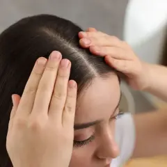 Kobieta masuje skórę głowy, zastanawiając się, ile trzymać peeling na głowie.