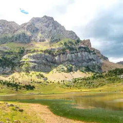 El ibón Piedrafita, un espejo de agua sereno, refleja la majestuosidad de las montañas rocosas y verdes.
