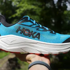 Niebieski but Hoka Challenger 8 z białym, grubym podeszwą i pomarańczowymi akcentami, gotowy na przygodę.