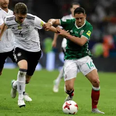 Piłkarze Niemiec i Meksyku walczą o piłkę na boisku. Intensywna gra podczas Pucharu Konfederacji UEFA.