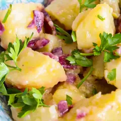 Salade de pommes de terre avec oignons rouges et persil frais dans un bol décoratif.