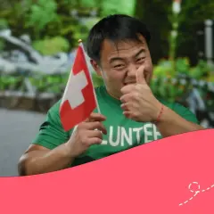 Hombre con bandera suiza y camiseta de voluntario, pulgar arriba. ¡Orgulloso de su voluntariado suizo!