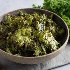 Crujientes chips de kale horneados en un tazón, perfectos para tus recetas con kale.