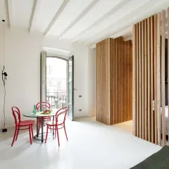 Una moderna parete con listelli di legno fai da te divide lo spazio, creando un angolo lettura e una zona notte.