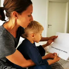 Mama czyta synkowi, kiedy czytać dziecku to ważny moment. Na kartce napisano "Rycerz przyjechał na koniu".