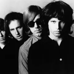 Czterech członków zespołu The Doors, w tym Jim Morrison z przodu, patrzą w obiektyw.