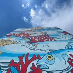 Un'onda di colori subacquei decora un muro a Roma, un'esplosione di vita marina e coralli rossi. Roma street art che porta il mare in città.