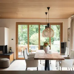 Moderne Inneneinrichtung mit viel Holz: Essbereich mit Holztisch, Kamin und großen Glasfronten zur Gartenseite.