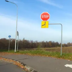 Znak STOP i znak informujący o drodze z pierwszeństwem łamanym. Na ścieżce rowerowej namalowane symbole pieszych i rowerzystów.