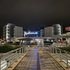 Nocny widok na hotel Radisson Blu Hamburg. Widać logo hotelu, znak Turkish Airlines i wejście.