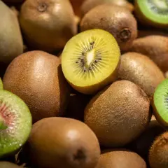 Ein Haufen Kiwis, einige ganz, andere aufgeschnitten, zeigen ihr grünes und gelbes Fruchtfleisch. Gut für den Schlaf, da sie Melatonin enthalten.