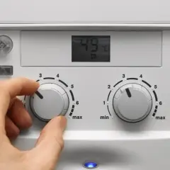 Mano che regola la caldaia spenta gas aperto. Il display mostra 49°C.