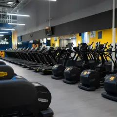 Rzędy bieżni i orbitreków w siłowni Just Gym. Chcesz wiedzieć, jak wejść na Multisport? Tu zaczynasz trening!