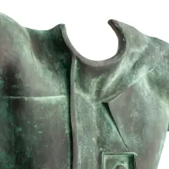 Fragment rzeźby z brązu przedstawiający tors z zieloną patyną.