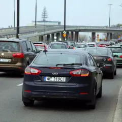 Korki na drodze, kierowcy czekają na zwrot za dojazdy do pracy. Widać rząd samochodów, w tym ciemnogranatowego Forda Mondeo.