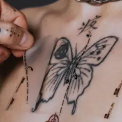 Frische tattoo pflege: Frischhaltefolie wird vorsichtig auf ein frisch gestochenes Schmetterlingstattoo auf der Brust aufgelegt.