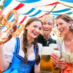 Trois amis joyeux célèbrent à l'Oktoberfest, un lieu festif, avec des bretzels géants et de la bière.