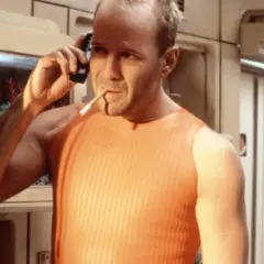Bruce Willis jako Korben Dallas, jeden z bohaterów "Piątego elementu", rozmawia przez telefon z papierosem w ustach.