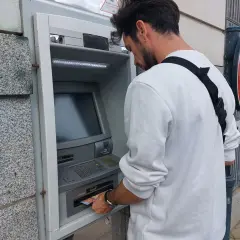 Un homme retire de l'argent à un distributeur automatique. Il suit les étapes pour comment retirer de l'argent.