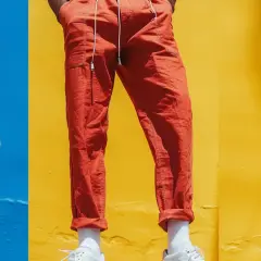 Tre män visar upp sina linnebyxor outfit herr i färgerna gult, orange och vitt mot en färgglad bakgrund.