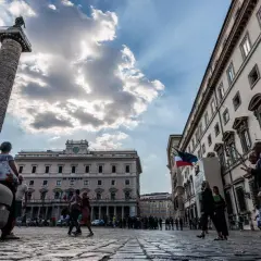 La Colonna di Marco Aurelio domina la piazza, con edifici storici e persone che passeggiano a Piazza Colonna, Roma.