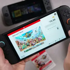 Ręce trzymają konsolę Nintendo Switch, na ekranie której wyświetla się okładka gry Mario Kart World. To może być najlepsza gra na Nintendo Switch!