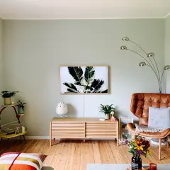 Gemütliche Wohnung mit hellen Farben: Ledersessel, Pflanzen und ein Bild mit Blattmotiv schaffen eine warme Atmosphäre.