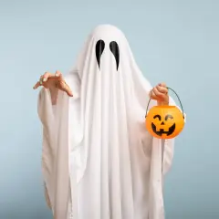 Bambino con costume da fantasma fai da te, tiene un cestino di caramelle a forma di zucca.