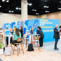 Attendees network at government trade shows, with a vibrant blue booth promoting "Turning Trade Shows Into Speakeasies.