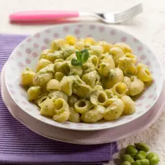 Un piatto di pasta con le fave fresche, condita con una crema verde e guarnita con menta.