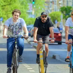 Drei Freunde fahren nebeneinander Fahrrad auf einer Straße.