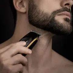Un homme utilise une tondeuse pour sculpter sa barbe, visant une barbe parfaite.