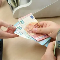 Ręce przekazują sobie banknoty euro. Czy na Węgrzech można płacić euro? Tak, euro jest powszechnie akceptowane.