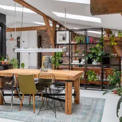 Jasne, oto propozycja:

Wnętrze z drewnianym stołem i mnóstwem roślin, tworzące przytulny biophilic design.