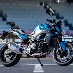 Niebiesko-szary motocykl BMW F900R na torze wyścigowym, gotowy do jazdy.