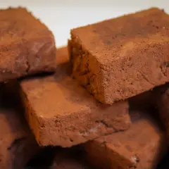 Stapel von schokoladigen Rohkost-Brownies, bestäubt mit Kakaopulver. Ein gesunder Genuss!
