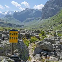 Panneau d'information dans le parc de la Vanoise, rappelant les règles pour les visiteurs, y compris la gestion du chien. Paysage montagneux rocailleux.