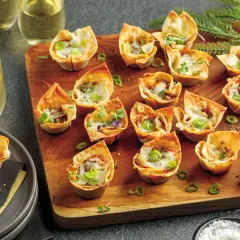 Petits feuilletés croustillants garnis d'effiloché de canard en feuille de brick, parsemés de ciboule et de fromage fondu.
