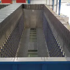 Duży, metalowy zbiornik przemysłowy z rzędami niebieskich elementów i kratownicami.