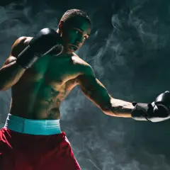 Boxer lands a powerful liver shot during training, smoke swirling around them.