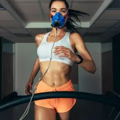 Kobieta w masce biegowa na bieżni, mierząca VO2max.